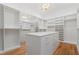 Spacious walk-in closet with custom shelving, mirrored doors, a marble island, and hardwood floors at 3267 Sewell Mill Rd, Marietta, GA 30062