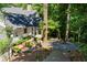 Beautiful home exterior with stone chimney, wooded landscaping, gravel area with fire pit, and wooden deck at 5205 Riverview Nw Rd, Atlanta, GA 30327