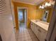Bathroom featuring yellow walls, a white sink vanity, and white tiled flooring at 6542 Cherry Tree Ln, Atlanta, GA 30328