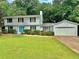 Charming two-story home featuring a well-manicured lawn, attached garage, and delightful blue front door at 6542 Cherry Tree Ln, Atlanta, GA 30328