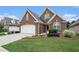 Charming brick home with an attached two-car garage, complemented by a lush green lawn and manicured landscaping at 2050 Woodberry Run Dr, Snellville, GA 30078