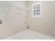 A bright laundry room with tile floors, featuring a window and hookups for washer and dryer at 2050 Woodberry Run Dr, Snellville, GA 30078