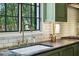 Close-up of the kitchen sink with brass fixtures, tile backsplash, and view of the backyard at 3086 E Pine Valley Nw Rd, Atlanta, GA 30305
