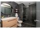 Modern bathroom with sleek, dark tiled walls, glass enclosed shower, round mirror, and contemporary vanity at 480 John Wesley Dobbs Ne Ave # 418, Atlanta, GA 30312