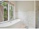 Luxurious bathroom featuring a soaking tub, a scale, and a large window with backyard views at 603 E Paces Ferry Ne Rd, Atlanta, GA 30305