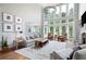 Bright living room with soaring windows, fireplace, chandelier, neutral colors and hardwood floors create cozy elegance at 105 Thorncliff Way, Acworth, GA 30101