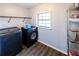 Functional laundry room includes a washing machine, dryer, shelving, and a window for natural light at 5479 Dorsett Shoals Rd, Douglasville, GA 30135