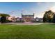 View of the grand home exterior with a circular driveway and manicured lawn at sunset at 1040 W Conway Nw Dr, Atlanta, GA 30327