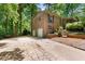 View of the home with a two-car garage and plenty of parking space, surrounded by mature trees at 3517 Greenway Dr, Marietta, GA 30008