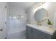 Bright bathroom featuring a round mirror, gray vanity, white countertop, marble tile shower, and gold hardware at 4085 Chadds Walk, Marietta, GA 30062