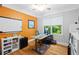 Bright home office with an adjustable desk, a large window, and an orange accent wall at 4731 Moon Chase Dr, Buford, GA 30519
