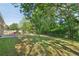 Large backyard with mature trees and partial view of the brick house at 6459 Paula Ct, Rex, GA 30273