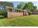 Quaint brick house with a red door and lush green lawn in a residential neighborhood at 6459 Paula Ct, Rex, GA 30273