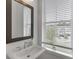 Bright bathroom featuring a pedestal sink, wood-framed mirror, and a window for natural light at 1117 Larkin Dr, Buford, GA 30518