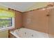 Bathroom with a whirlpool bathtub surrounded by tile, with a large window for natural light at 2377 Pine Mountain Rd, Kennesaw, GA 30152