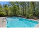 Sparkling backyard pool surrounded by mature trees and greenery offers a refreshing escape at 2377 Pine Mountain Rd, Kennesaw, GA 30152