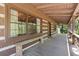 Covered porch of a log home with a wooden bench, windows, and a door at 2377 Pine Mountain Rd, Kennesaw, GA 30152