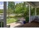 Backyard view from the covered porch with mature trees, green grass, and an old swing at 10559 Serenbe Ln, Chattahoochee Hills, GA 30268