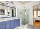 Luxury bathroom featuring double sinks, a glass-enclosed shower, and a glimpse of an adjacent bedroom with chandelier at 10559 Serenbe Ln, Chattahoochee Hills, GA 30268