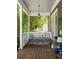 Charming porch with a cushioned swing, wood floors, and a view to the yard at 10559 Serenbe Ln, Chattahoochee Hills, GA 30268