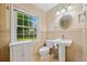This cozy bathroom offers tiled walls, bright natural light, and traditional pedestal sink at 1448 Drayton Woods Dr, Tucker, GA 30084