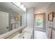 Bright bathroom offers a large mirror, neutral paint, a window, and decorative wall art above the towel rack at 150 Shady Grove Ln, Alpharetta, GA 30009