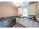 Functional laundry room boasts modern washer and dryer units, granite countertops, and ample cabinet space above the sink at 150 Shady Grove Ln, Alpharetta, GA 30009