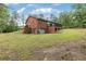Back exterior of the house with a grassy lawn and wooded view at 3881 Moore Rd, Ellenwood, GA 30294