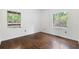 An empty bedroom with hardwood floors and white walls, lit by two windows at 3881 Moore Rd, Ellenwood, GA 30294