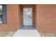 Close-up of the brick entryway featuring a secure screen door and classic wall sconces at 3881 Moore Rd, Ellenwood, GA 30294