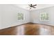Spacious primary bedroom with hardwood floors, ceiling fan, and natural light from two windows at 3881 Moore Rd, Ellenwood, GA 30294