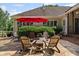 Serene backyard featuring a stone patio with outdoor seating, lush greenery, and a vibrant red umbrella at 11155 Highfield Chase Dr, Johns Creek, GA 30097