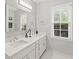 Elegant bathroom with a double sink vanity, large mirror, and a window offering pleasant outdoor views at 11155 Highfield Chase Dr, Johns Creek, GA 30097