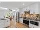 Bright kitchen features white cabinets, granite counters and stainless appliances near breakfast nook at 11155 Highfield Chase Dr, Johns Creek, GA 30097