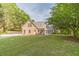 Backyard view of home featuring large lawn, mature trees and a rear covered porch at 1609 Holly Ridge Dr, Loganville, GA 30052