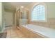 Elegant bathroom with tiled floors, glass shower and soaking tub under a large arched window at 1609 Holly Ridge Dr, Loganville, GA 30052