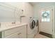 Well-lit laundry room with stainless steel washer and dryer, utility sink, and direct access to the exterior at 1609 Holly Ridge Dr, Loganville, GA 30052