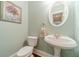 Charming powder room featuring a pedestal sink, oval mirror, and a beautifully painted accent wall at 1609 Holly Ridge Dr, Loganville, GA 30052