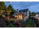 A beautiful backyard at dusk featuring an outdoor dining area, a playset, and mature landscaping at 2580 Glaramara Ter, Cumming, GA 30041
