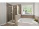 Bathroom featuring a glass shower, a soaking tub, tile surround, and a bright window at 2580 Glaramara Ter, Cumming, GA 30041