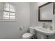 Clean powder room featuring a modern pedestal sink, toilet, mirror, and window for a fresh and airy feel at 2580 Glaramara Ter, Cumming, GA 30041