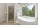 Bright bathroom with a soaking tub next to the window, paired with a glass-door shower area at 110 Hawks Bnd, Canton, GA 30115