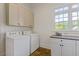 Well-lit laundry room with washer, dryer, granite countertop, white cabinets, and natural light at 110 Hawks Bnd, Canton, GA 30115