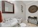 Elegant powder room featuring a pedestal sink, decorative mirror, and stylish wall art at 7505 Antique Barn Ave, Cumming, GA 30041
