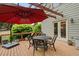 Outdoor deck with a dining set, red umbrella, and a view of green trees at 7505 Antique Barn Ave, Cumming, GA 30041