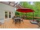 Outdoor deck featuring a table and chairs, red umbrella, and a view of the wooded backyard at 7505 Antique Barn Ave, Cumming, GA 30041