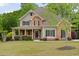 Inviting two-story home with stone accents, a cozy front porch, and lush green lawn at 7505 Antique Barn Ave, Cumming, GA 30041