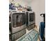 Functional laundry room featuring modern washer and dryer units with shelving for storage at 7505 Antique Barn Ave, Cumming, GA 30041