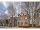Two-story gray brick home featuring red shutters, black fencing and mature trees lining the street at 319 Barbados Ln, Suwanee, GA 30024