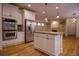 Open-concept kitchen featuring white cabinets, a center island, stainless appliances, and hardwood flooring at 319 Barbados Ln, Suwanee, GA 30024